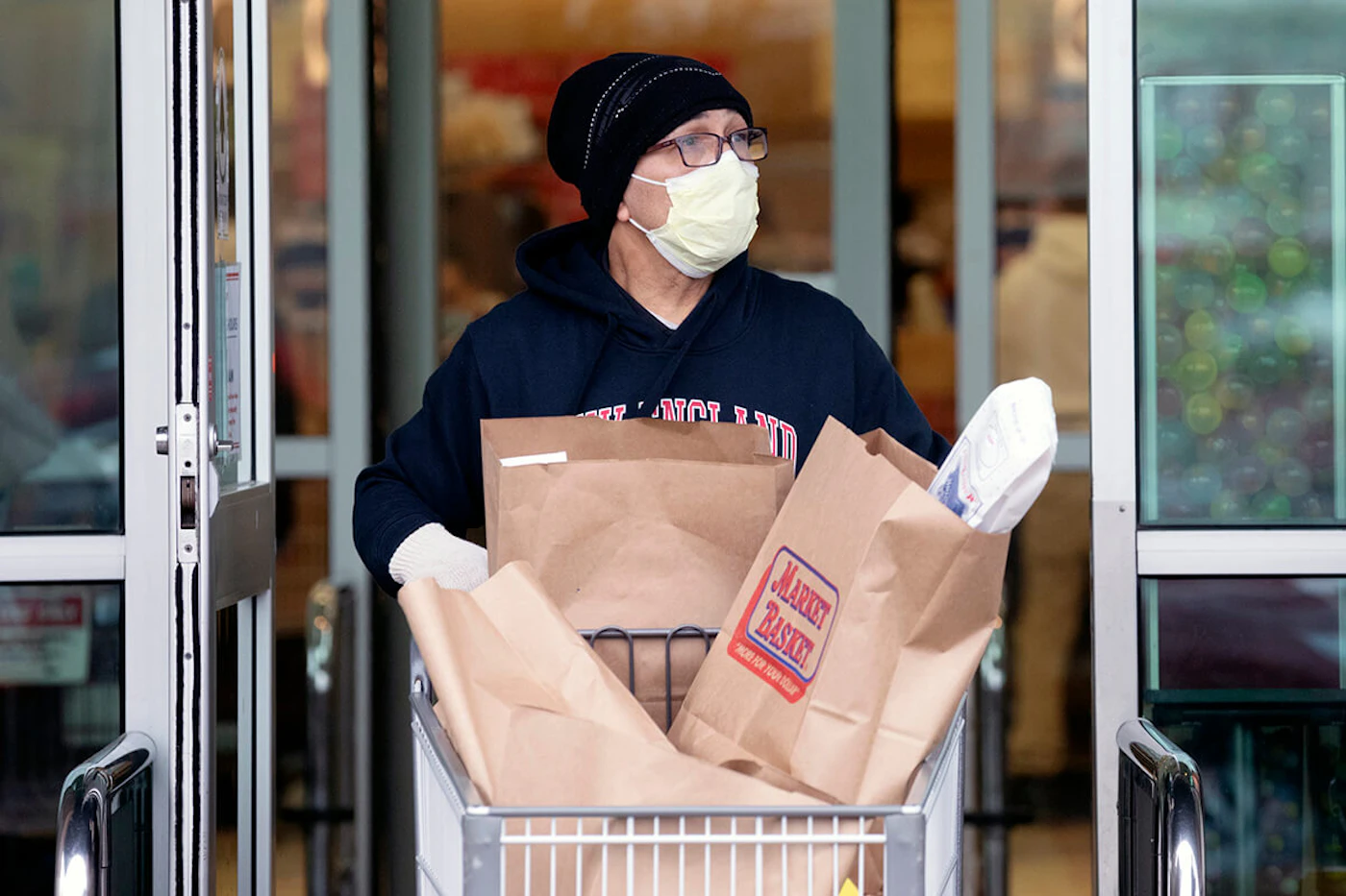 man wearing mask using shopping cart full of groceries