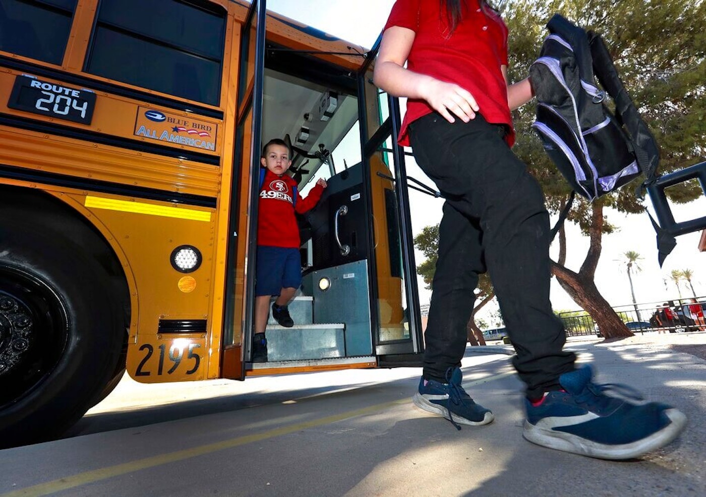 two children walking off a school bus