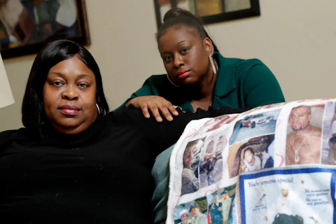 two Black women holding quilt with photos of relative who was killed by police