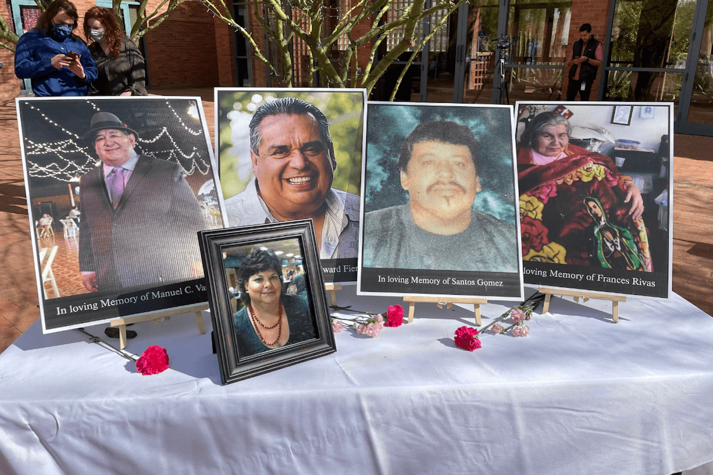 framed photos of people lost to COVID set up on a table with flowers