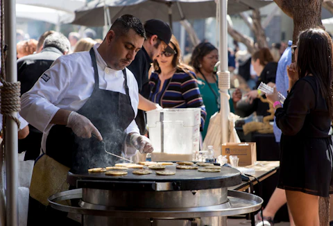 Nationally, food service added 61,000 jobs in March, the most of any industry, but total bar and restaurant employment was still below pre-pandemic levels. In this 2017 photo, Jose Rojas prepares food for the Artizen Crafted American Kitchen & Bar at the Devour Culinary Classic in Phoenix. (Photo by Megan Bridgeman/Cronkite News)
