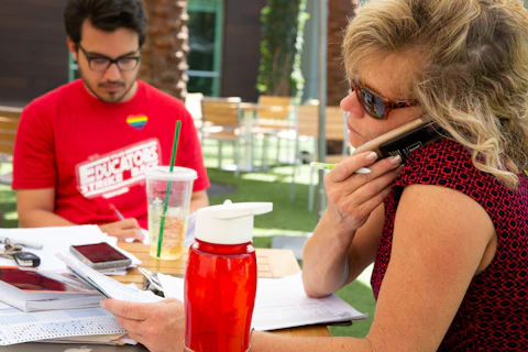 Christine Marsh answers a campaign phone call while she records grades from her English students in between campaign events at a "grade-in" with her fellow striking teacher Karson Shipp to demonstrate that they're still working in the interest of their students during the educators strike for public education funding on April 28 at Desert Ridge Marketplace in Phoenix, Ariz.