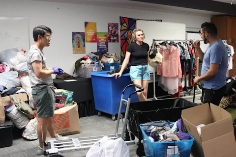 Staff members, from left, John Ngo, Abby Loza and Eric Morales, finish sorting clothing on the last day of the drive. (Photo by Samia Salahi/Cronkite News)