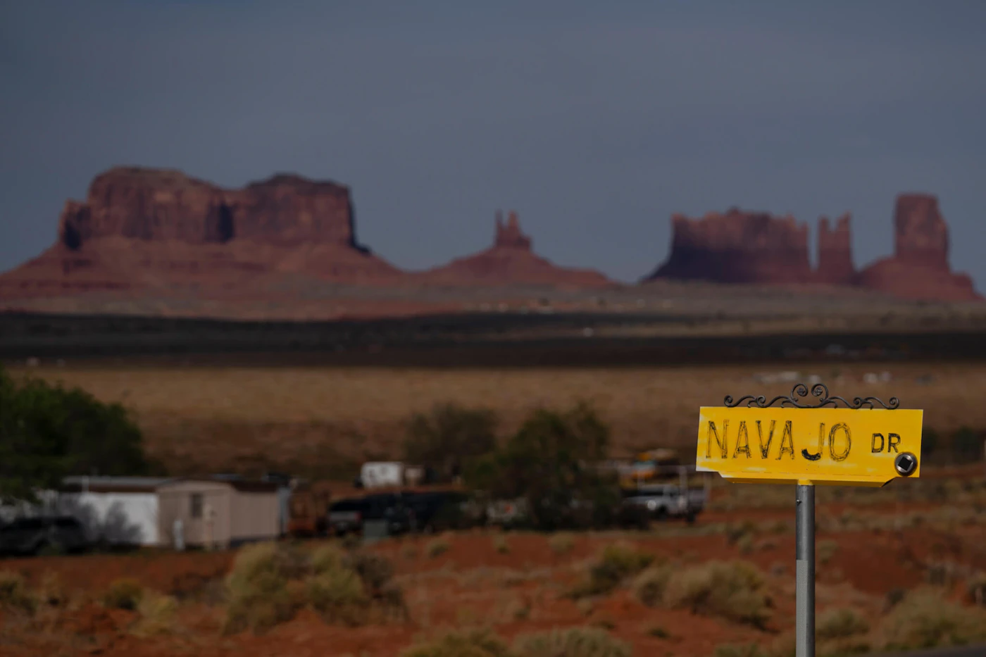 FILE - A sign marks Navajo Drive, as Sentinel Mesa, homes and other structures in Oljato-Monument Valley, Utah, on the Navajo Reservation, stand in the distance, on April 30, 2020.  The Supreme Court has ruled against the Navajo Nation in a dispute involving water from the drought-stricken Colorado River. States that draw water from the river — Arizona, Nevada and Colorado — and water districts in California had urged the court to decide for them, and that's what the justices did in a 5-4 ruling. (AP Photo/Carolyn Kaster, File)