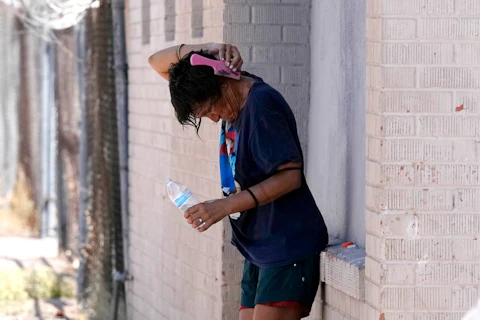 A person tries to cool off in the shade Tuesday, July 18, 2023, in Phoenix. (AP Photo/Ross D. Franklin)