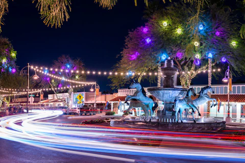 Scottsdale, AZ - February 9 2020: Traffic at night around Bob Parks' Bronze Horse Fountain in Old Town Scottsdale's 5th Avenue Shopping district. (Shutterstock Photo/kenelamb photographics)