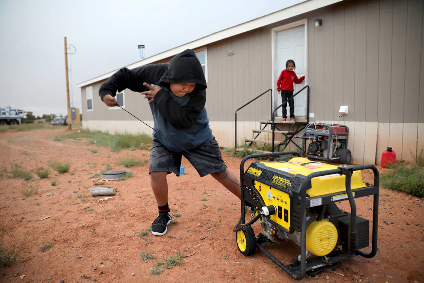 FILE - Jayden Long starts the generator behind his Kaibeto home on the Navajo Reservation in Arizona, May 8, 2019, so that he can charge his cell phone inside the family home. The U.S. Interior Department on Tuesday, Aug. 15, 2023, unveiled a new program to bring electricity to more homes in Native American communities as the Biden administration looks to funnel more money toward climate and renewable energy projects. (AP Photo/Jake Bacon, File)