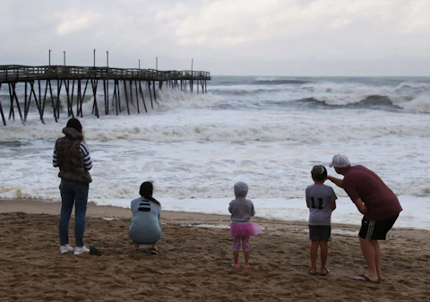 People look out at the Avalon Pier that was damaged by Hurricane Dorian in Kill Devil Hills in 2019. Local health officials say hurricane response prepared them for their successful COVID vaccine drive. (Photo by Mark Wilson/Getty Images)