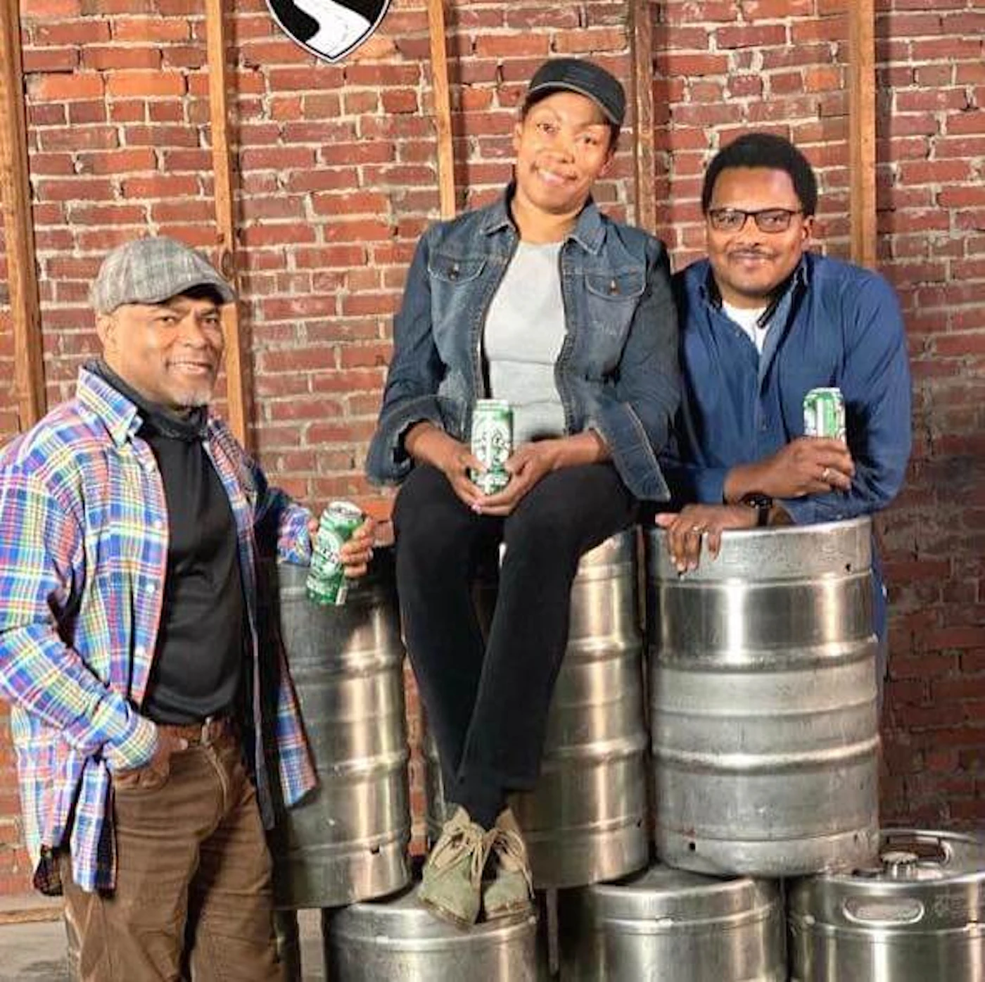 Carl (left) and Pernell Beatty (right) flank their sister Celeste, the owner of Harlem Brew South, in her taproom. The warehouse is the site of Operation Dixie, a historical and successful labor campaign in 1946. More than 10,000 tobacco workers, mostly women, gathered from around the state and voted to unionize for better working conditions. Harlem Brew's lager is named '1946' in tribute.