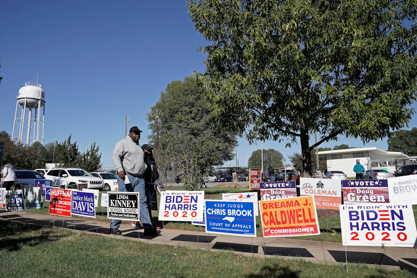 Voters walk past campaign signs at the Graham Civic Center polling location in Graham, N.C., Tuesday, Nov. 3, 2020. (AP Photo/Gerry Broome)