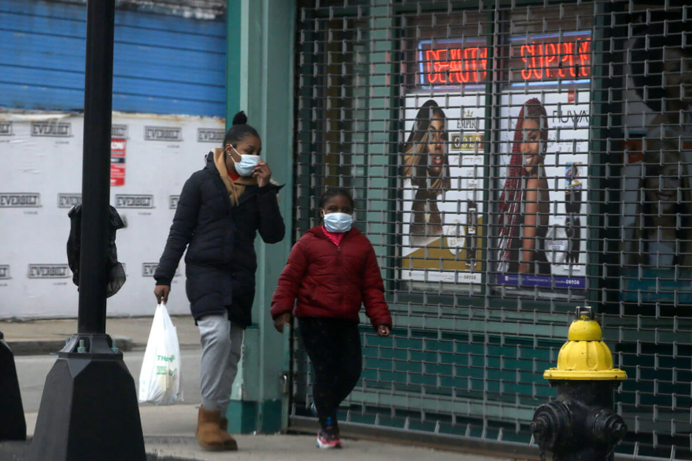 Passers-by walk past a closed shop, in Boston. (AP Photo/Steven Senne)