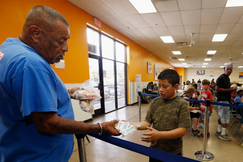 Volunteer Monroy Martinez, left, hands out a free to-go lunch to a boy at the St. Mary's Food Bank Alliance due to the Arizona teachers strike and closure of schools Thursday, April 26, 2018, in Phoenix. (AP Photo/Ross D. Franklin)