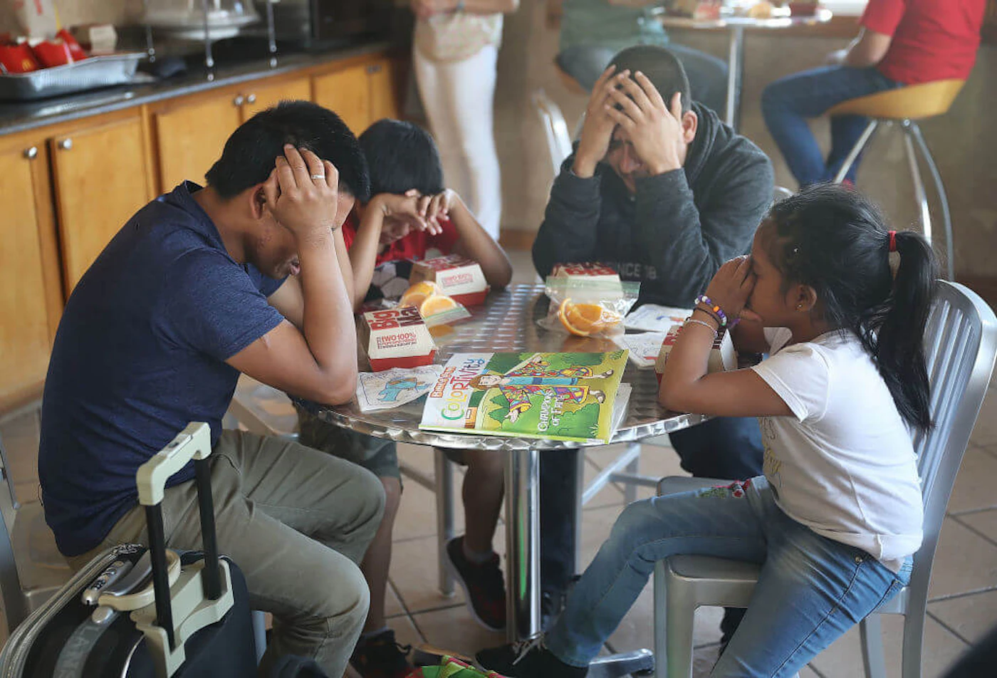 Nery (L) and Emiliano (2nd R) pray with their children over the McDonald's food that was given to them as they are cared for in an Annunciation House facility after they were reunited on July 25, 2018 in El Paso, Texas. Nery and Emiliano, originally from Guatamala, were reunited with their children at an ICE processing center about two months after they were separated when they tried to cross into the United States. trump cannot deport children