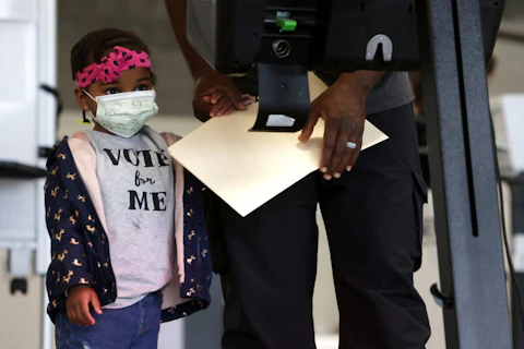 Two-year-old Aissatou Barry accompanies her father to vote at an early voting center at Union Market October 27, 2020 in Washington, DC. (Photo by Alex Wong/Getty Images)