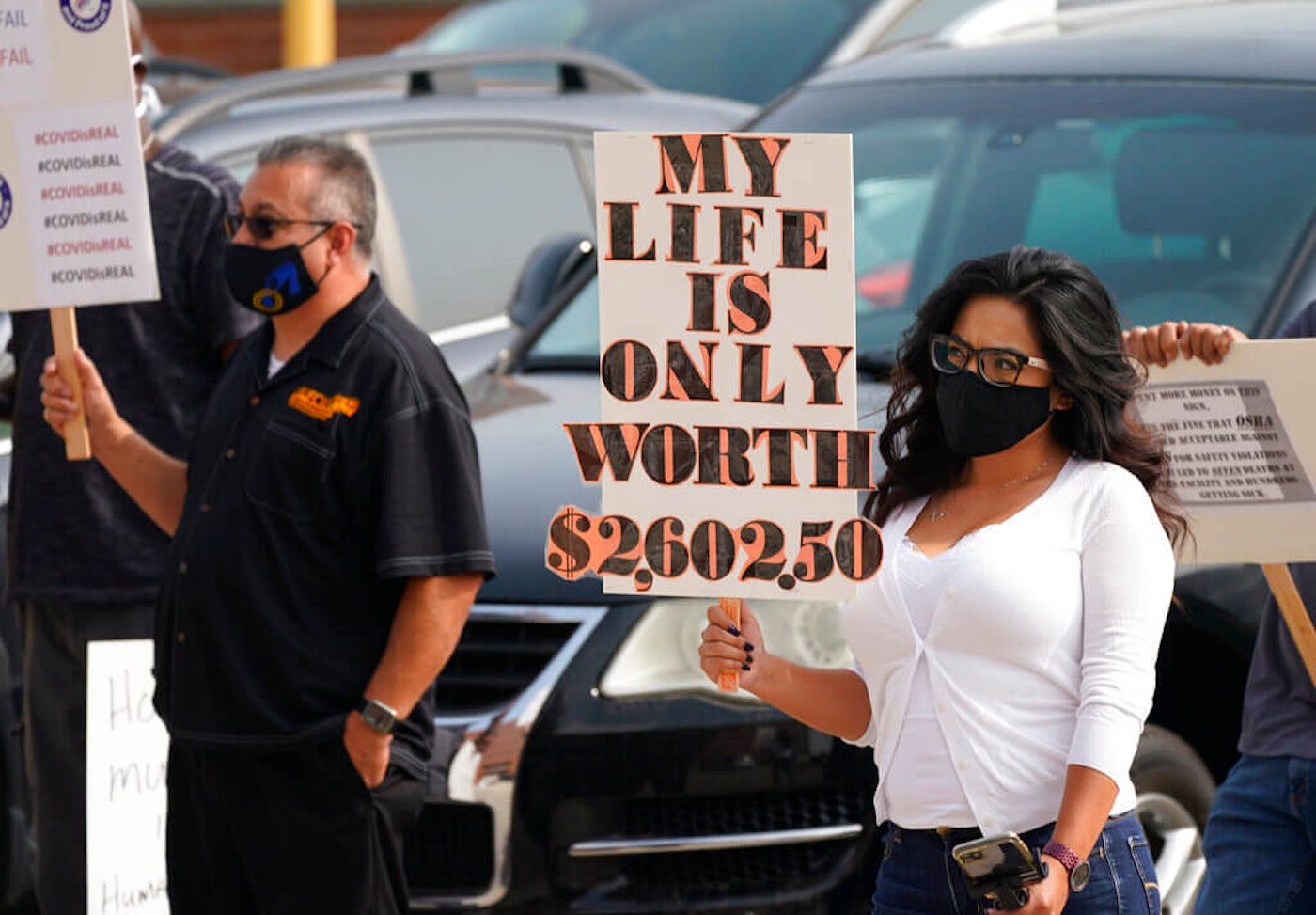 Jimena Peterson waves a placard during a protest outside the offices of the Occupational Safety and Health Administration, Sept. 16, 2020, in downtown Denver. The protest was staged by the union representing employees at a Colorado meatpacking plant where six workers died of COVID-19 and hundreds more were infected this past spring. AP Photo/David Zalubowski.