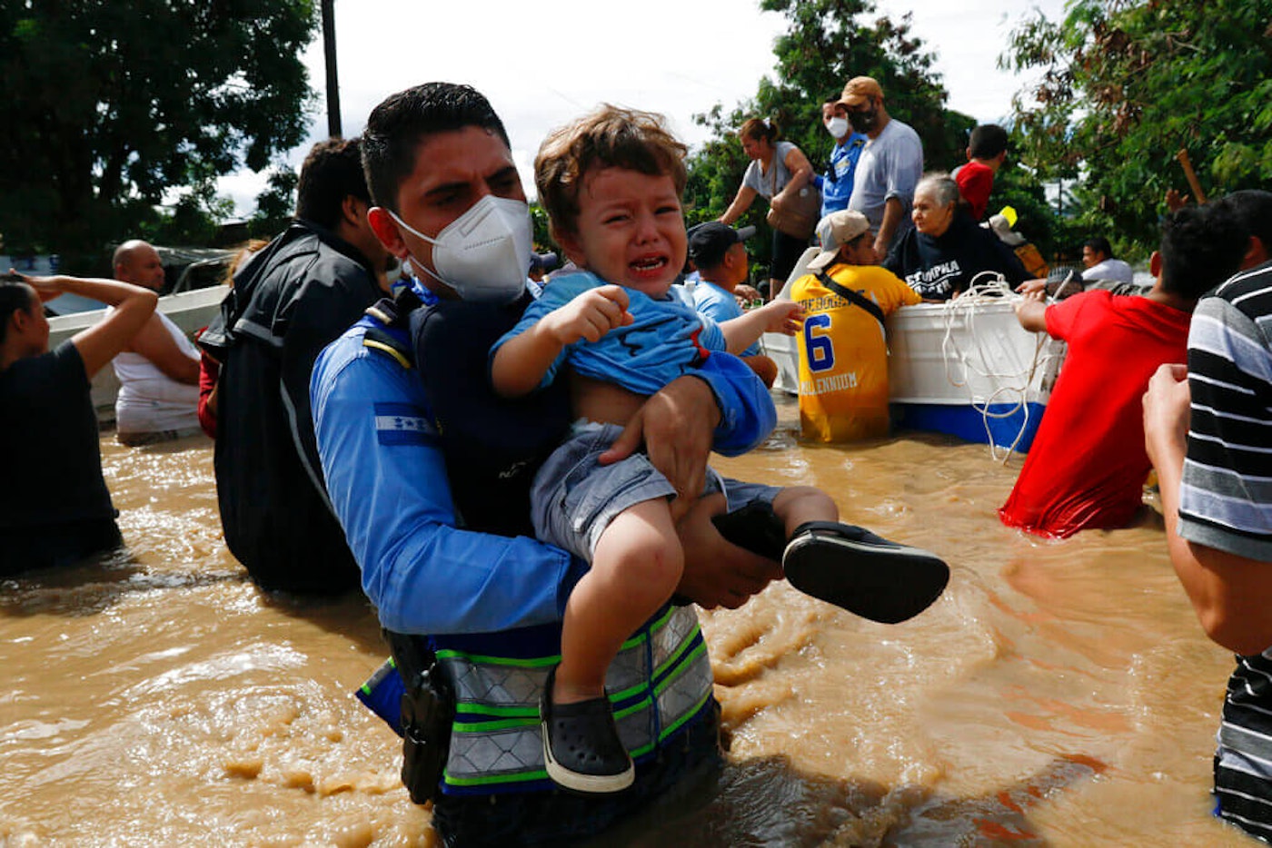 A toddler is carried over a flooded street in the aftermath of Hurricane Eta in Jerusalén, Honduras, Thursday, Nov. 5, 2020. The storm that hit Nicaragua as a Category 4 hurricane on Tuesday had become more of a vast tropical rainstorm, but it was advancing so slowly and dumping so much rain that much of Central America remained on high alert. help-hurricane-eta