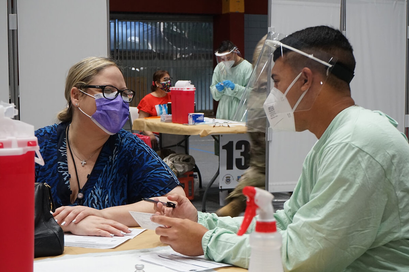 Spc. Abner Torres Nieves speaks with a person before a COVID-19 vaccination at Pedrín Zorrilla Coliseum in San Juan, Puerto Rico. National-Guard-Vaccination-PR
