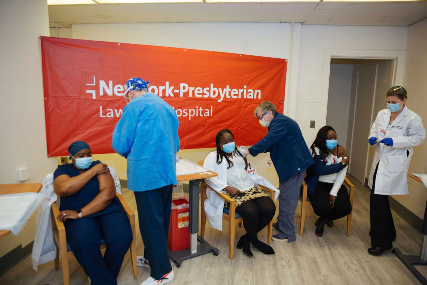 Doctors inject sisters Claudia Scott-Mighty, left, Althea Scott-Bonaparte, who are patient care directors, and Christine Scott, an ICU nurse, with their second shot of the Pfizer vaccine at NewYork-Presbyterian Lawrence Hospital on Friday, Jan. 8, 2021. (AP Photo/Kevin Hagen).