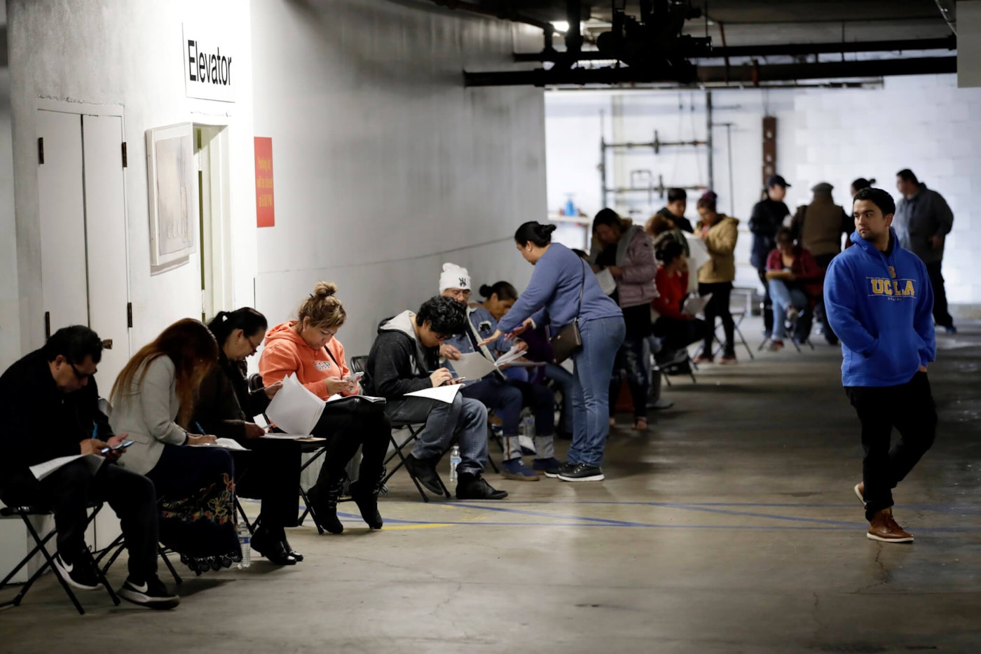 In this March 13, 2020 file photo, unionized hospitality workers wait in line in a basement garage to apply for unemployment benefits at the Hospitality Training Academy in Los Angeles. (AP Photo/Marcio Jose Sanchez, File)