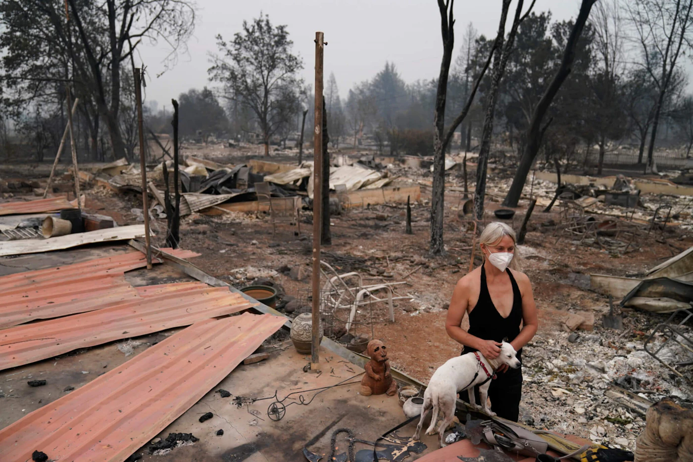 Eden McCarthy pets her dog Hina in the rubble of her home destroyed by the Almeda Fire, Thursday, Sept. 10, 2020, in Talent, Ore. (AP Photo/John Locher)