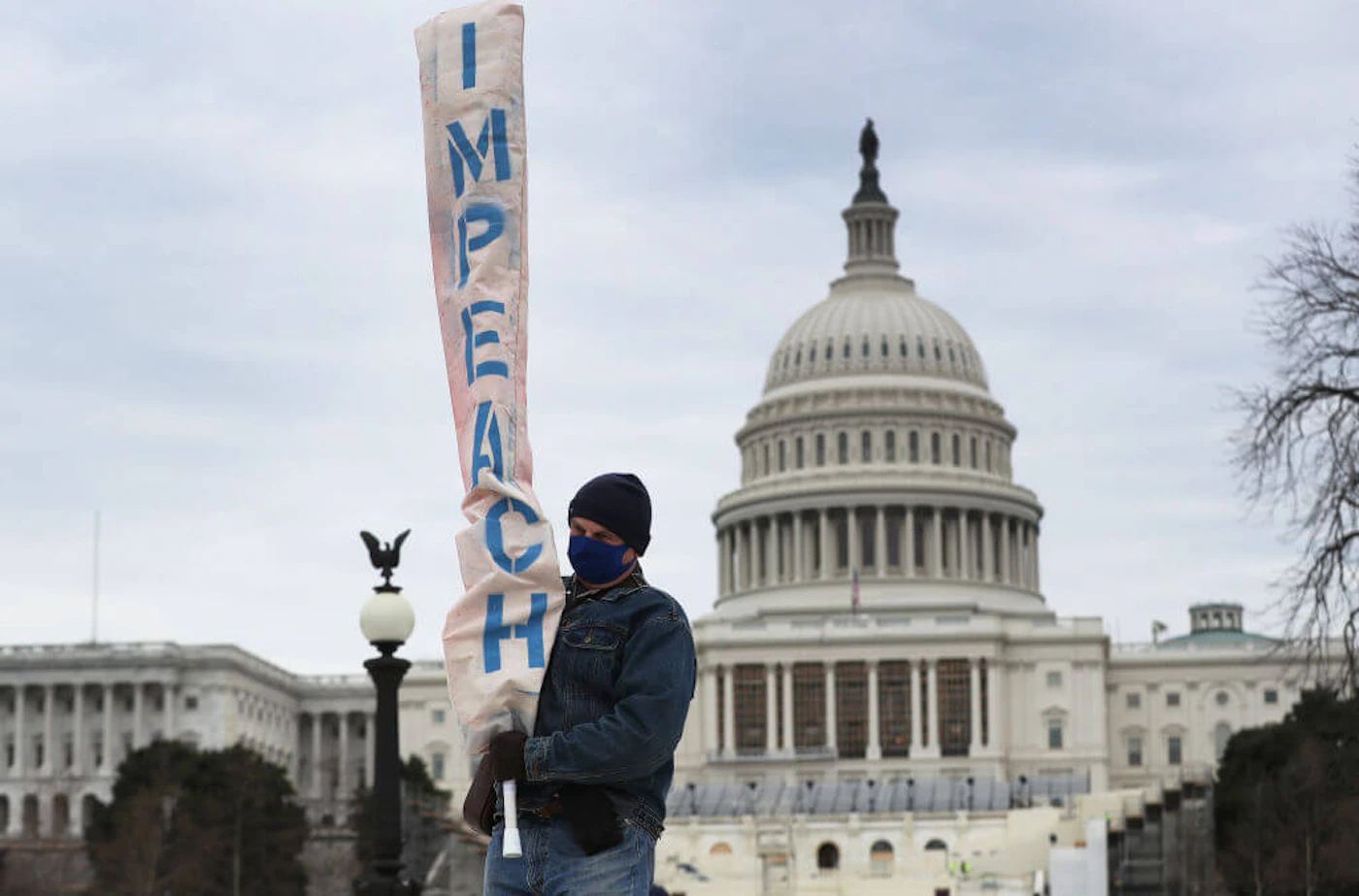 WASHINGTON, DC - JANUARY 08: Bill Zawacki carries a banner that reads "impeach" near the U.S. Capitol Building, two days after a pro-Trump mob broke into the building on January 08, 2021 in Washington, DC. Democratic congressional leaders threatened to impeach President Donald Trump for encouraging the mob that stormed the Capitol Building. (Photo by Joe Raedle/Getty Images)