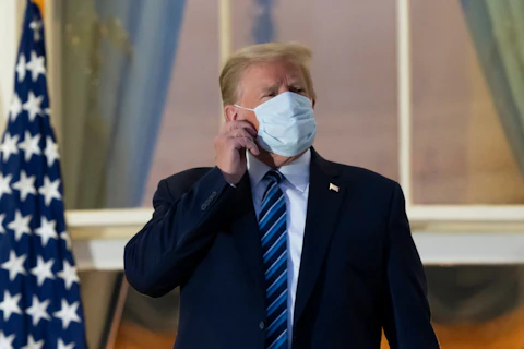 President Donald Trump removes his mask as he stands on the Blue Room Balcony upon returning to the White House after leaving Walter Reed National Military Medical Center. Trump announced he tested positive for COVID-19 on Oct. 2.