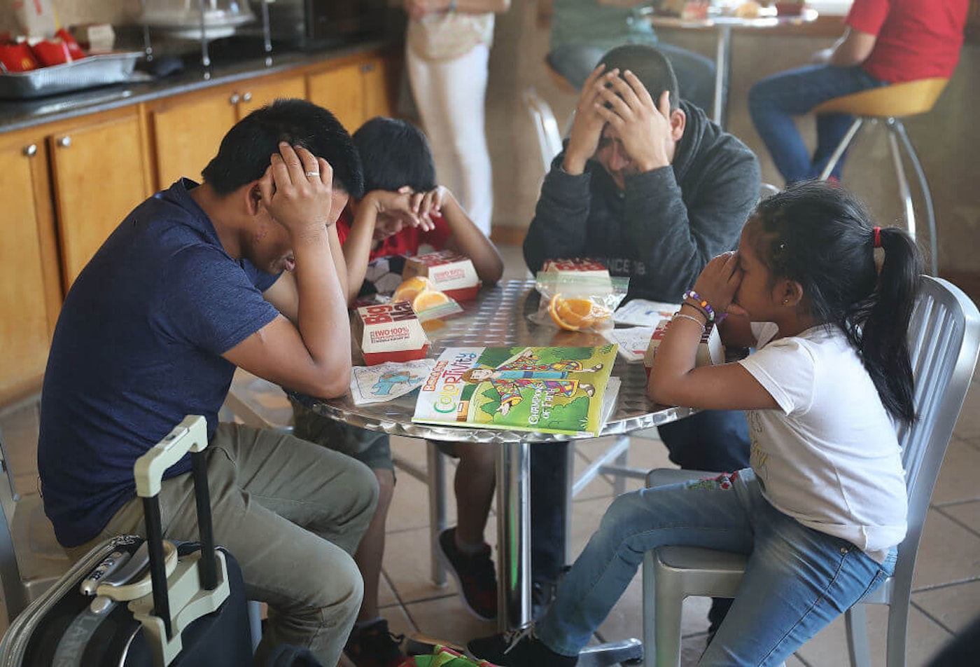 Nery (L) and Emiliano (2nd R) pray with their children over the McDonald's food that was given to them as they are cared for in an Annunciation House facility after they were reunited on July 25, 2018 in El Paso, Texas. Nery and Emiliano, originally from Guatamala, were reunited with their children at an ICE processing center about two months after they were separated when they tried to cross into the United States. 545-children-trump