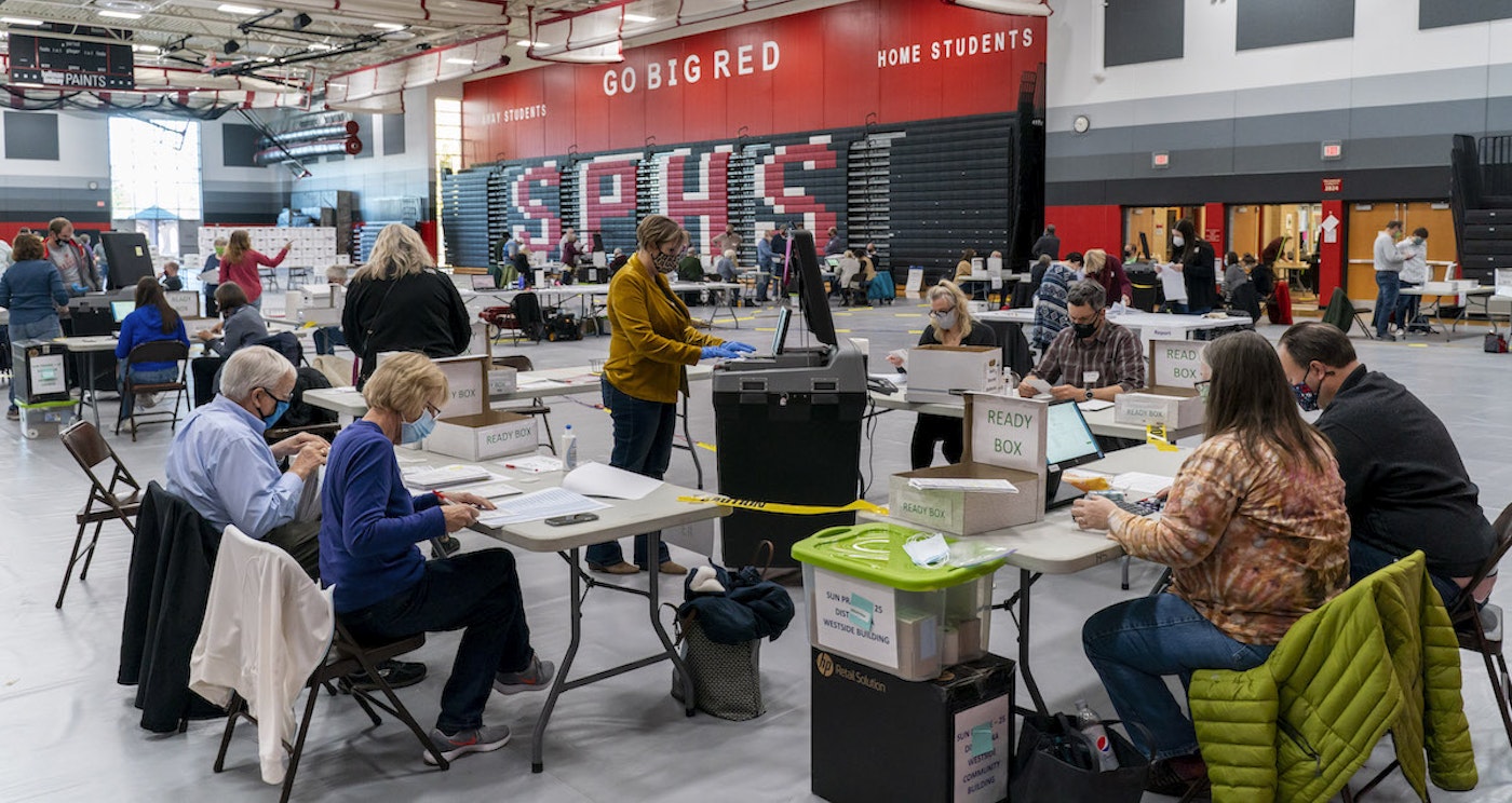 Poll worker Rebecca Brandt, center, feeds a voting tabulation machine with absentee ballots in the gym at Sun Prairie High School on Nov. 3 in Sun Prairie. The entire gym was dedicated to counting the absentee ballots. (Photo by Andy Manis/Getty Images)