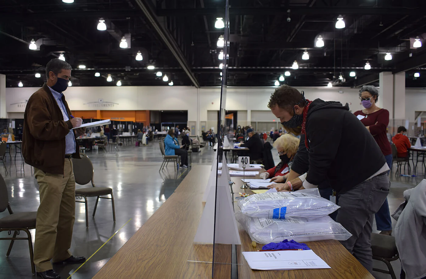 At left, Bill Bridge, a Trump-supporting recount observer, watches election officials work last November at the Wisconsin Center in Milwaukee. The 2020 presidential election has repeatedly been shown to have been secure and accurate despite numerous recounts, challenges, and ongoing baseless claims.(Photo by Jonathon Sadowski)