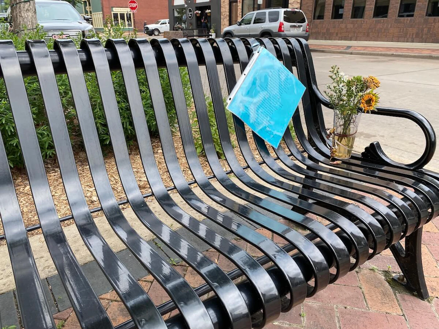 Flowers and a poem are left on a bench in memory of Marilyn Roeber, a homeless woman who often occupied the bench in downtown Eau Claire. Roeber, 66, was found dead on the bench last week. (Photo by Julian Emerson)