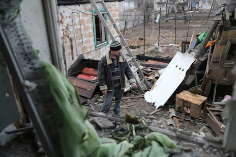A local citizen stands between debris of his house following Ukrainian shelling in the territory controlled by pro-Russian militants, eastern Ukraine, Thursday, Feb. 24, 2022. Russian troops have launched a three-pronged assault on Ukraine that opened with air and missile strikes on Ukrainian military facilities and included ground troops invading from Crimea. (AP Photo/Alexei Alexandrov)