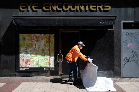 A worker folds up a tarp after attaching a poster to a shuttered business in Philadelphia, Monday, May 4, 2020. The Center City District and Mural Arts Philadelphia posted the original works on multiple locations in an effort to enhance the neighborhood awash with business shuttered to help curb the spread of coronavirus. (AP Photo/Matt Rourke)
