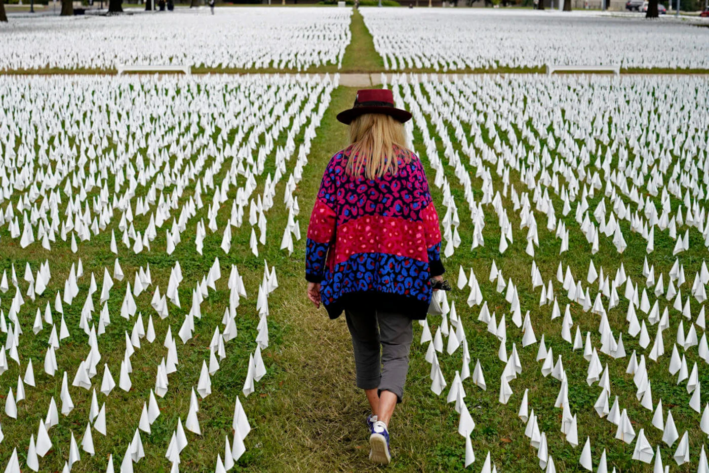 In this Oct. 27, 2020, Artist Suzanne Brennan Firstenberg walks among thousands of white flags planted in remembrance of Americans who have died of COVID-19 near Robert F. Kennedy Memorial Stadium in Washington. (AP Photo/Patrick Semansky, File)
