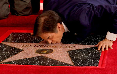 Mehmet Oz, the former host of "The Dr. Oz Show," kisses his new star on the Hollywood Walk of Fame during a ceremony on Friday, Feb. 11, 2022, in Los Angeles. (AP Photo/Chris Pizzello)