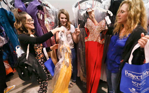 Mary Girton, right, holds a dress as her daughters, 16-year-old Annie, left, and 17-year-old Gabi, look over potential prom gowns in Pittsburgh, Saturday, March 3, 2018. Eligible students from schools in Alegheny County were at the Project Prom Gown Giveaway to select free dresses and accessories to wear for their high school prom on the first day of the week long event sponsored by the Allegheny County Department of Human Services and the National Council of Jewish Women at their Thriftique store. (AP Photo/Keith Srakocic)