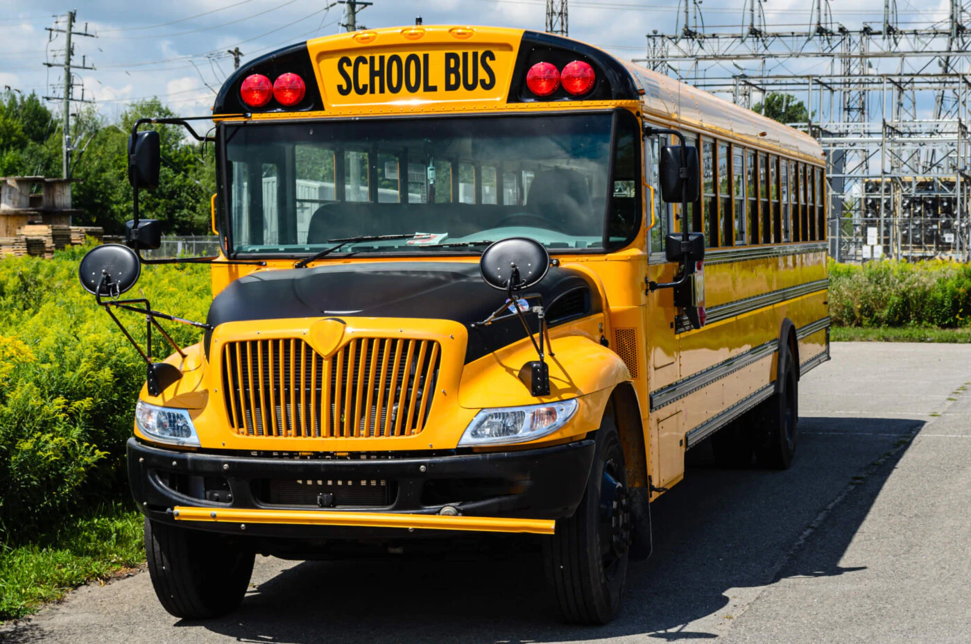 Front view of a yellow school bus parked in front of a hydro sub-station. (Getty Images)