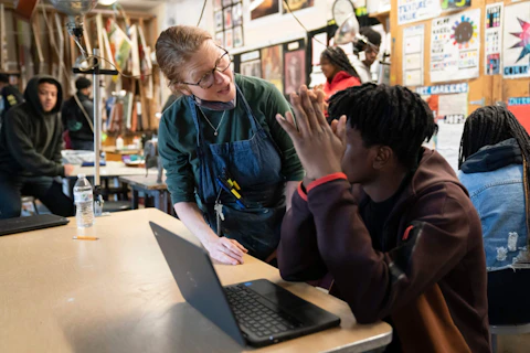 Art teacher Alyce Grunt speaks with a student at Penn Wood High School in Lansdowne, Pa., Wednesday, May 3, 2023. As schools across the country struggle to find teachers to hire, more governors are pushing for pay increases and bonuses for the beleaguered profession.  (AP Photo/Matt Rourke)