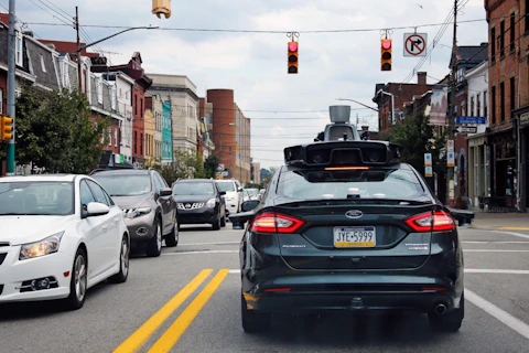FILE - In this Wednesday, Sept. 14, 2016, file photo, a self-driving Uber car stops at a red light on Liberty Avenue through the Bloomfield neighborhood of Pittsburgh. In just a few years, well-mannered self-driving robotaxis will share the roads with reckless, law-breaking human drivers. The prospect is causing migraines for the people developing the robocars and is slowing their development. But experts say eventually the cars will coexist with human drivers on real roads. (AP Photo/Gene J. Puskar, File)