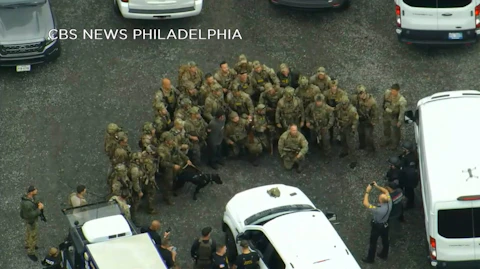 In this image from video provided by CBS NEWS Philadelphia, law enforcement officers pose for a group photo with Danelo Cavalcante after his capture in rural Pennsylvania on Wednesday, Sept. 13, 2023. The murderer who brazenly escaped from a Pennsylvania jail was captured in the woods by a team of tactical officers, bringing an end to an intensive search that terrified residents as the fugitive broke into homes for food, changed his appearance and stole a van and rifle during two weeks on the run. (CBS NEWS Philadelphia KYW-TV via AP)