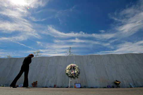 Visitors to the Flight 93 National Memorial pause at The Wall of Names, containing the names of the 40 passengers and crew who died in the crash of United Flight 93 following a memorial service in Shanksville, Pa., Tuesday, Sept. 11, 2012. (AP Photo/Gene J. Puskar)
