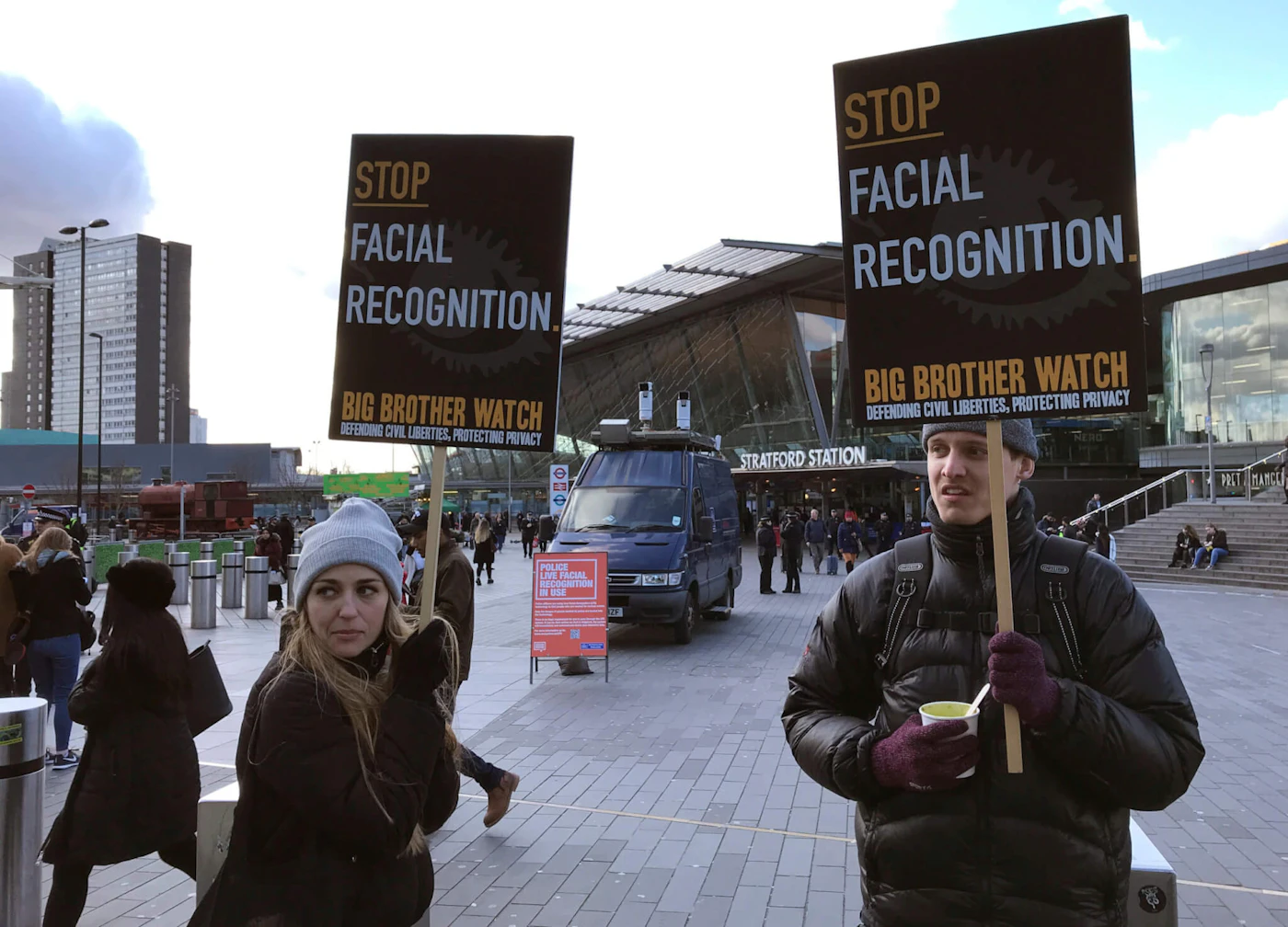 In this Feb. 11, 2020, file photo, Silkie Carlo, left, demonstrates in front of a mobile police facial recognition facility outside a shopping centre in London. A Black man who says he was unjustly arrested because facial recognition technology mistakenly identified him as a suspected shoplifter is calling for a public apology from Detroit police. And for the department to abandon its use of the controversial technology. (AP Photo/Kelvin Chan, File)