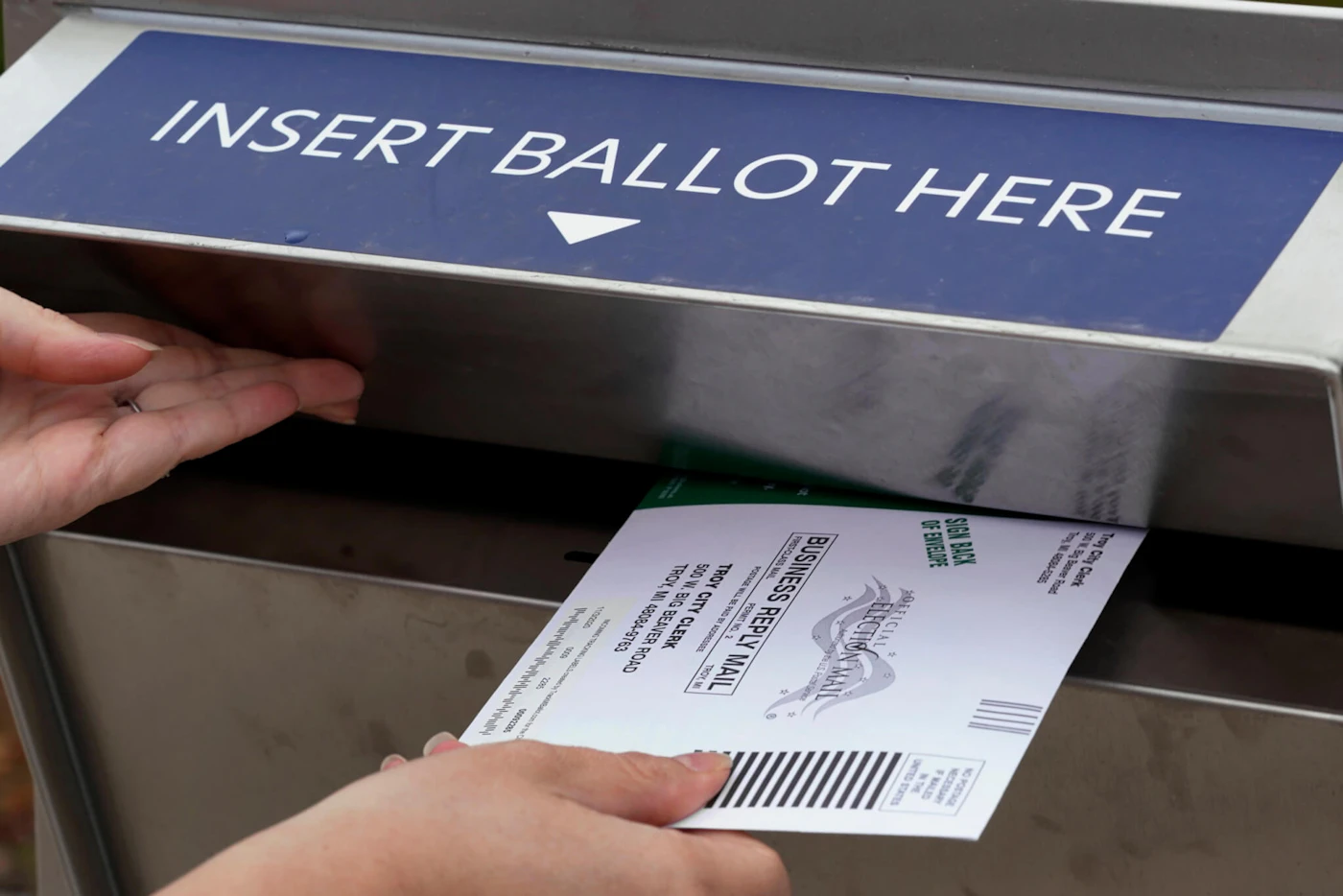Nikki Schueller inserts her absentee voter ballot into a drop box in Troy, Mich., Thursday, Oct. 15, 2020. (AP Photo/Paul Sancya)