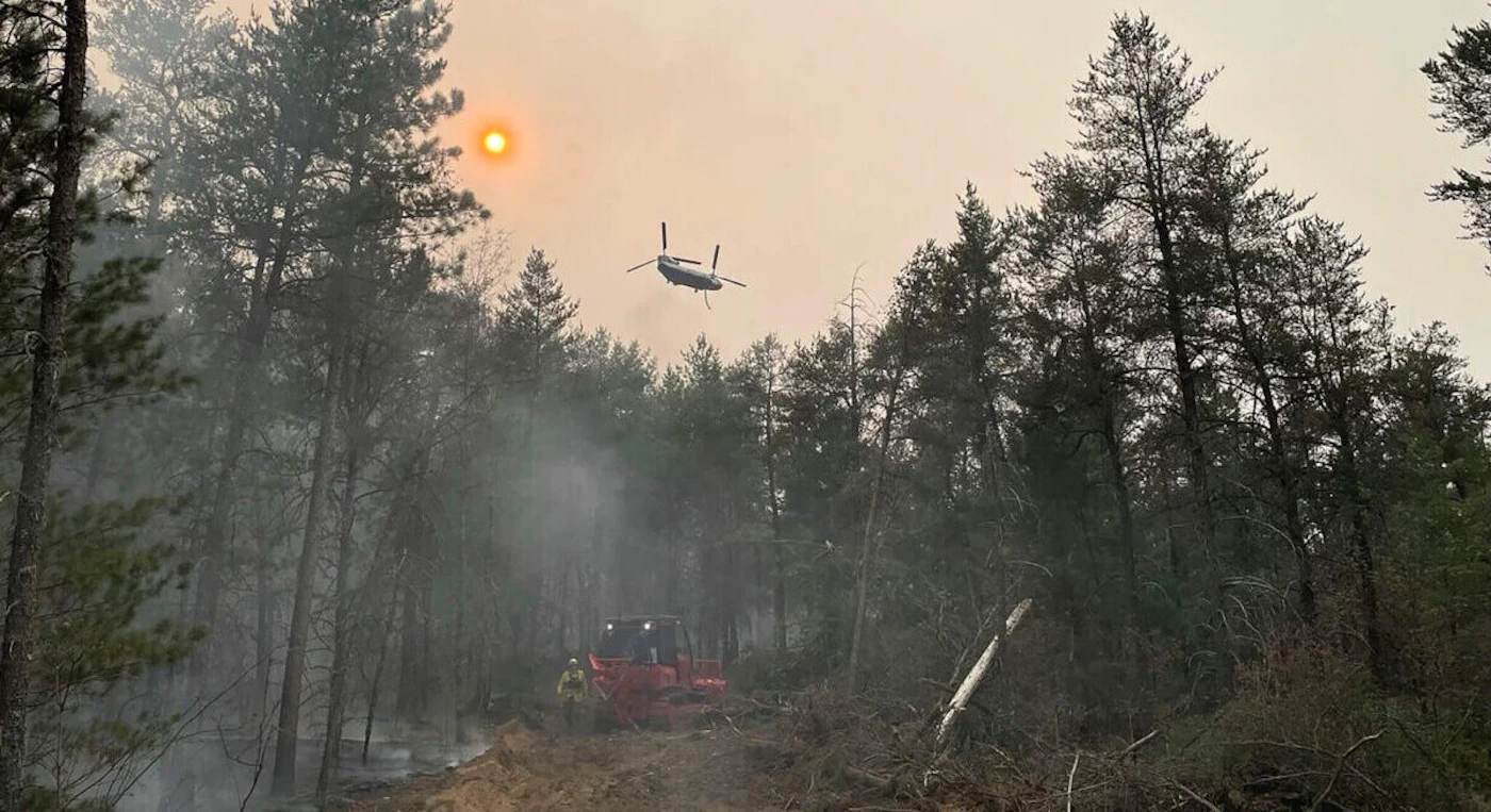 This image provided by the Michigan Department of Natural Resources shows emergency personnel, aircraft and heavy equipment being used to suppress the wildfire near Grayling. (The Michigan Department of Natural Resources via AP)