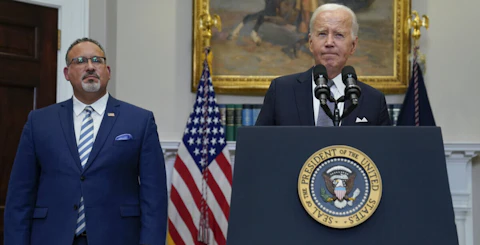 FILE - President Joe Biden pauses as he speaks in the Roosevelt Room of the White House, Friday, June 30, 2023, in Washington. Education Secretary Miguel Cardona listens at left. After a series of major blows to his agenda from the Supreme Court, Biden is intent on making sure it is voters — not the justices of the high court — who have the final say. “Republicans snatched away the hope that they were given,” Biden said hours after the high court overturned his plan to forgive a majority of the country’s federal student loans. (AP Photo/Evan Vucci, File)