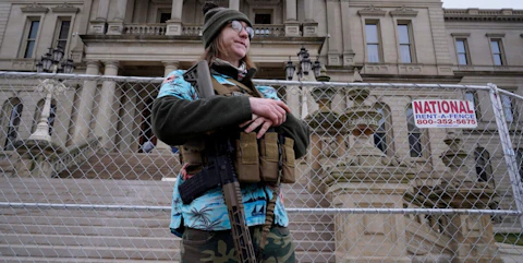 Timothy Teagan, a member of the Boogaloo Bois movement, stands with his rifle outside the state capitol in Lansing in 2021. (AP Photo/Paul Sancya)